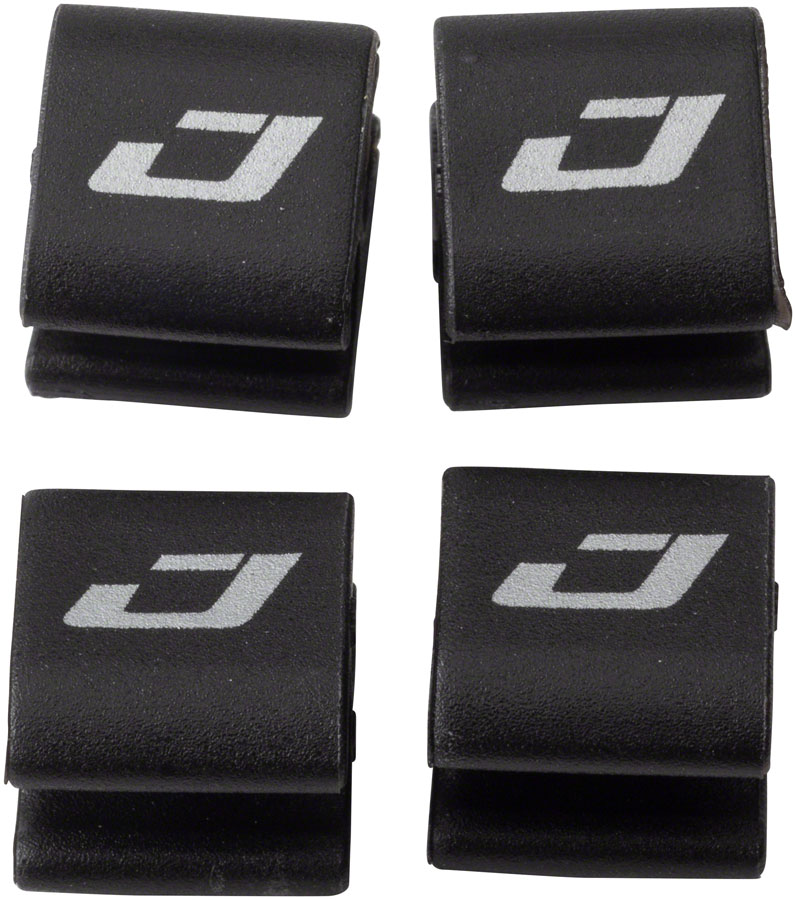 Accessoires vélo: Quatre crochets pour cables et gaines de vitesses et de freins Jagwire Wire Hook posés à plat sur un fond blanc